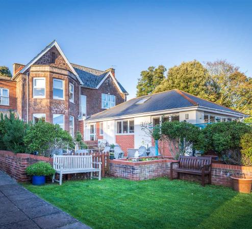 View of Parkland House building from garden with lawn, planting and seating