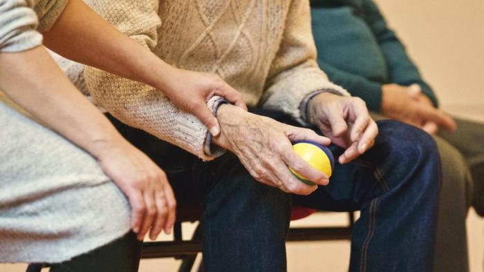 Staff helping an elderly person with a ball