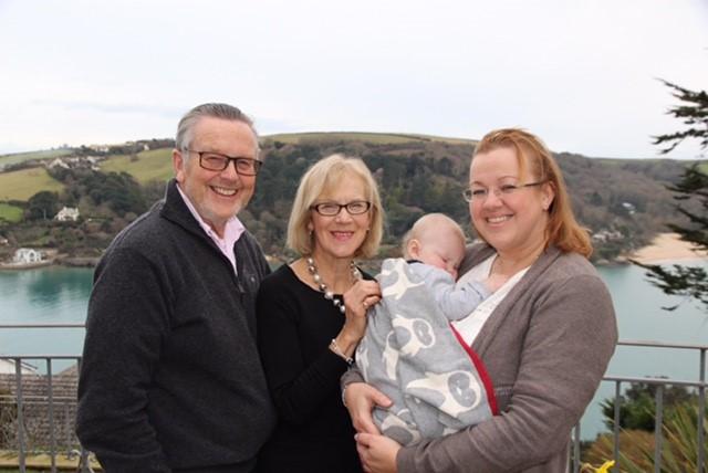 Managing Director Louise holding her son as a baby with her parents. In the background Salcombe